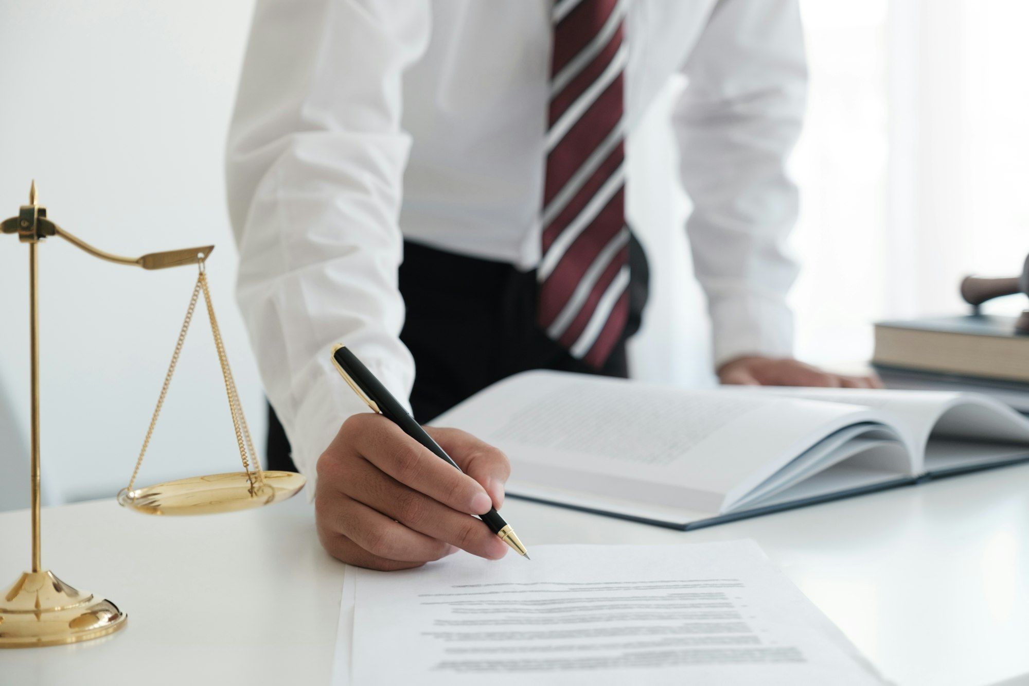 Lawyer Signing Documents Near Mallet And Scales